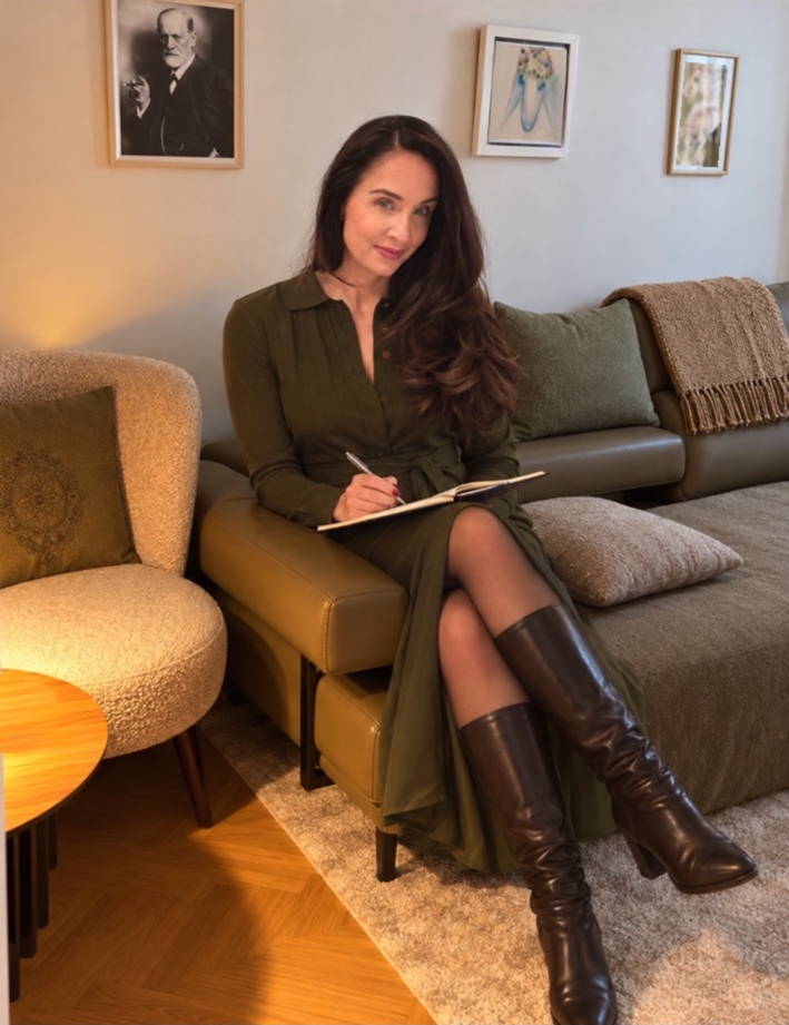 Dr. Sarah Deutsch im grünen Kleid mit Notizbuch in ihrer Praxis
